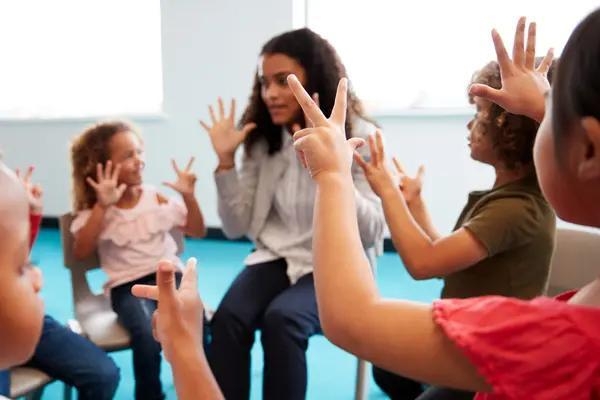 Woman and children in a circle holding their hands up