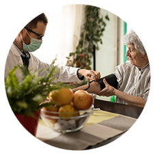 Doctor wearing a mask checking an elderly woman's blood pressure