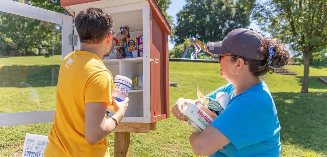 Two volunteers stocking a free pantry