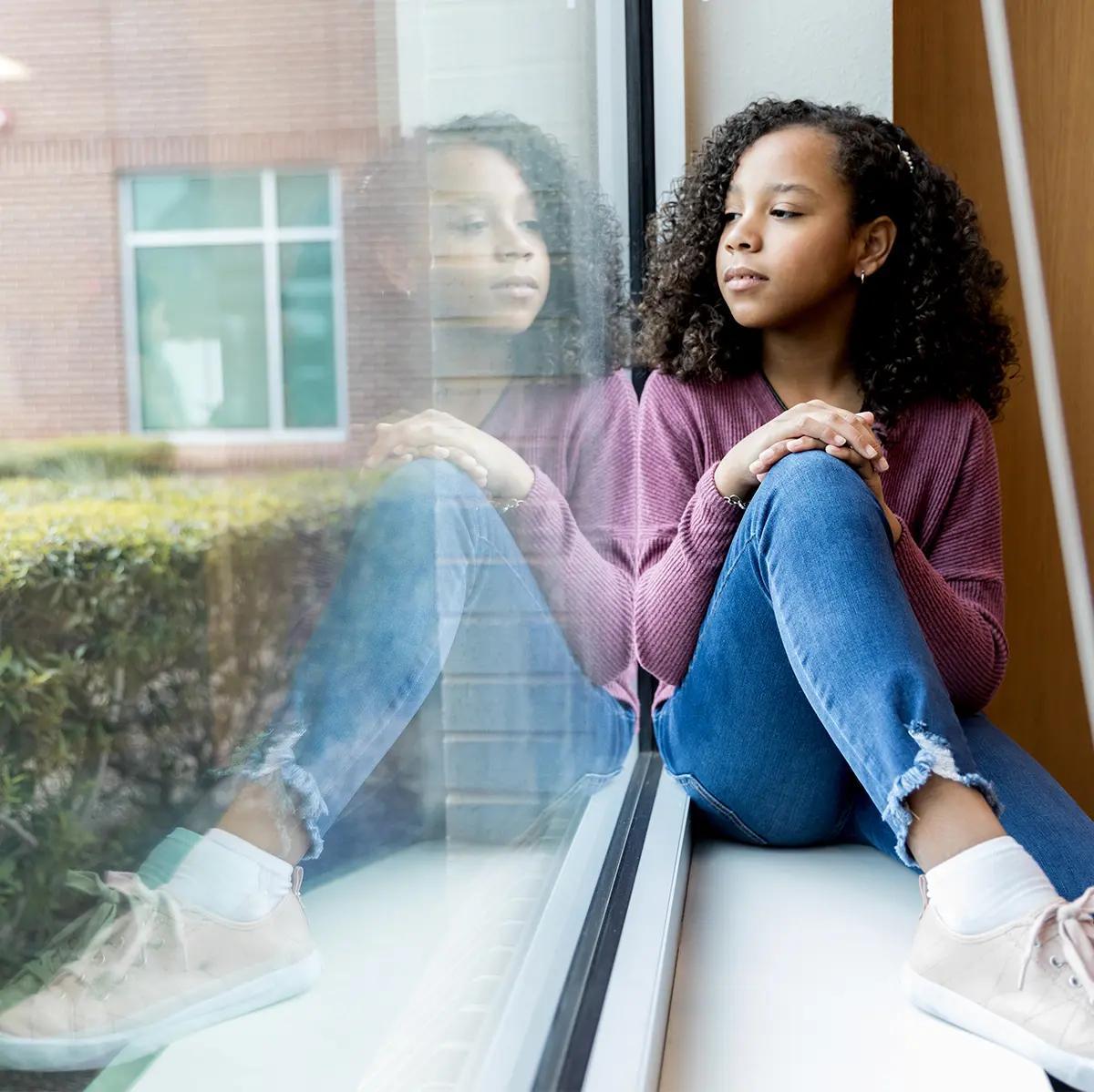 Girl sitting on a window seat looking out the window