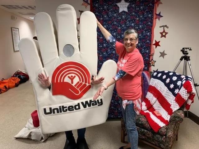 Volunteer standing with person wearing a hand costume